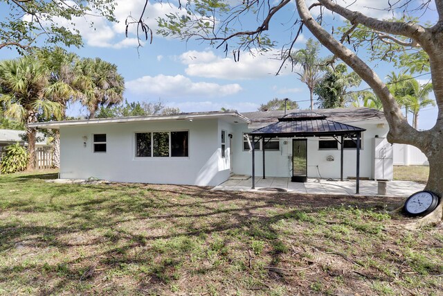 back of property with a gazebo, a lawn, and a patio area