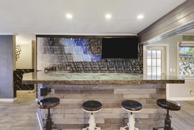 bar featuring light stone counters and light wood-type flooring