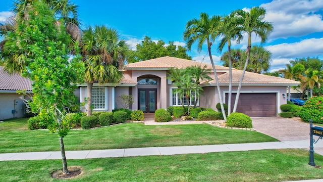 mediterranean / spanish house featuring a front yard, french doors, and a garage