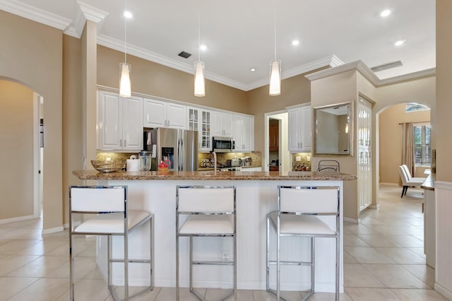 kitchen with white cabinetry, kitchen peninsula, stainless steel appliances, hanging light fixtures, and light stone counters