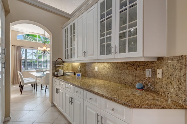 kitchen with light tile patterned floors, backsplash, and white cabinets