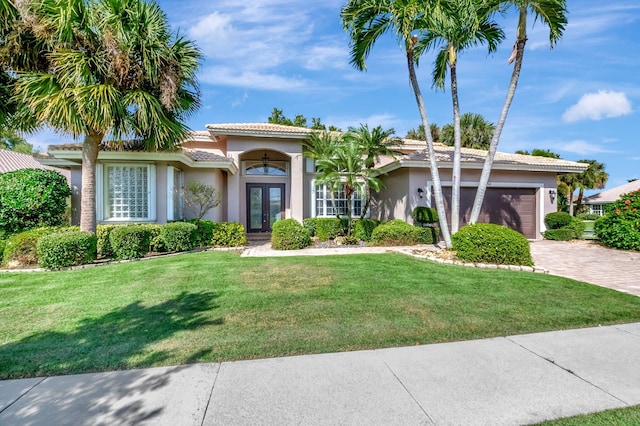 mediterranean / spanish-style house with french doors, a garage, and a front yard