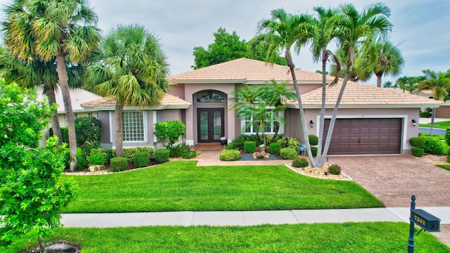 mediterranean / spanish-style house featuring a front yard, a garage, and french doors