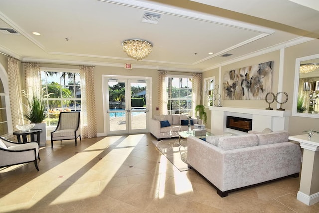 living room with a tray ceiling, light tile patterned flooring, french doors, a chandelier, and crown molding