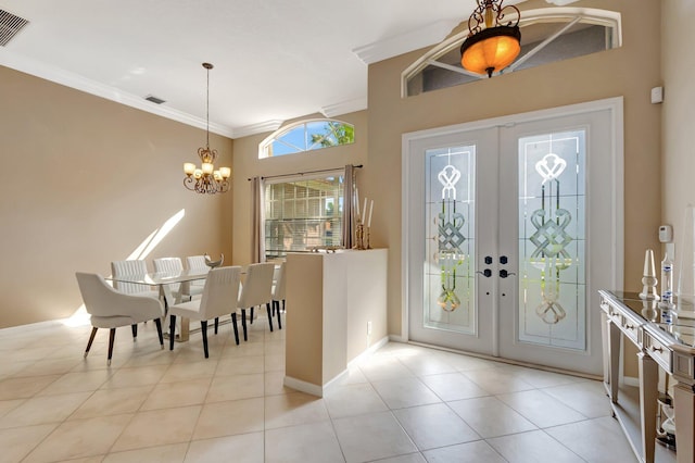 entrance foyer featuring a chandelier, light tile patterned floors, crown molding, and french doors