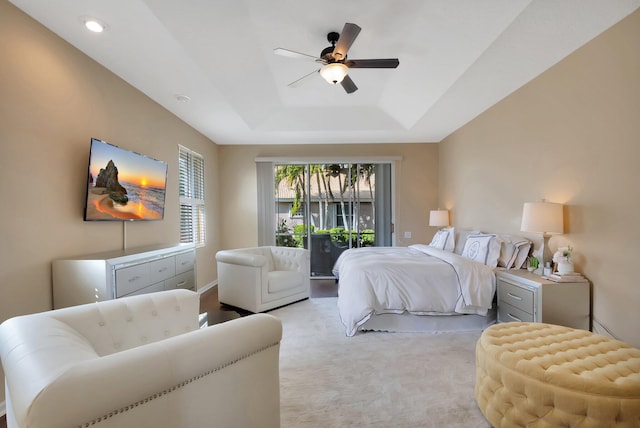 carpeted bedroom with ceiling fan, access to exterior, and a raised ceiling