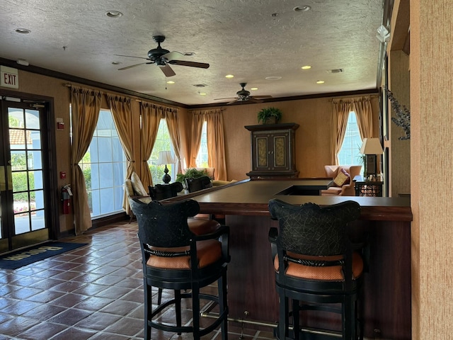 bar featuring a textured ceiling, ceiling fan, and ornamental molding