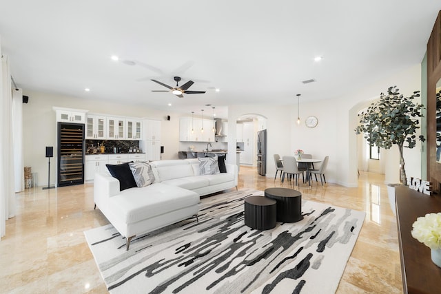 living room featuring ceiling fan with notable chandelier and wine cooler