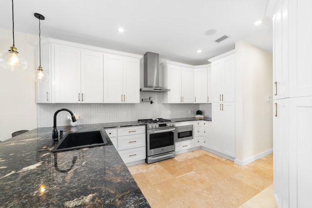 kitchen with wall chimney range hood, sink, stainless steel gas stove, decorative light fixtures, and white cabinetry