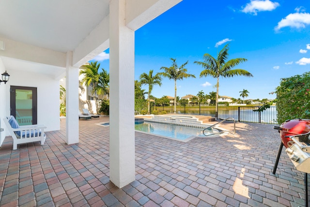 view of pool with a patio area, a water view, and an in ground hot tub