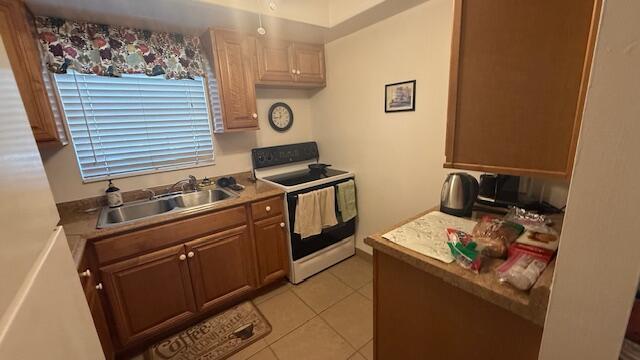 kitchen featuring white range with electric stovetop, light tile patterned floors, and sink