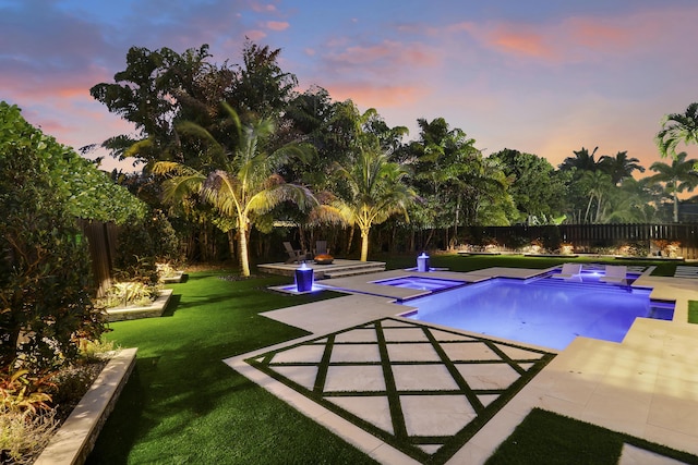 pool at dusk with a yard, an in ground hot tub, and a patio