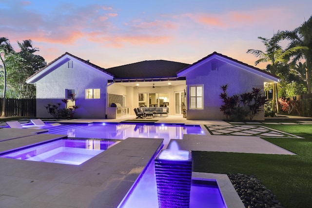 pool at dusk with outdoor lounge area, ceiling fan, a patio area, and an in ground hot tub