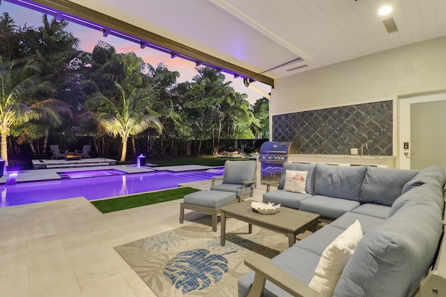 pool at dusk with an outdoor living space, grilling area, and a patio area