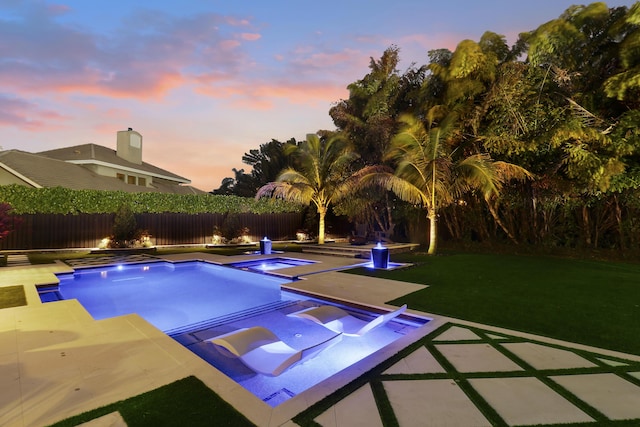 pool at dusk with a yard, an in ground hot tub, and a patio