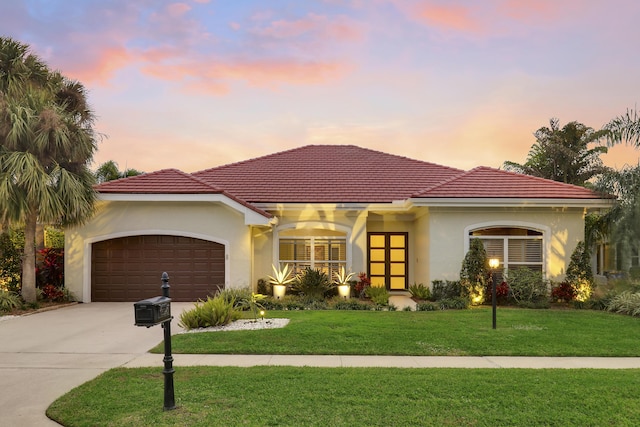 mediterranean / spanish-style home featuring a yard and a garage