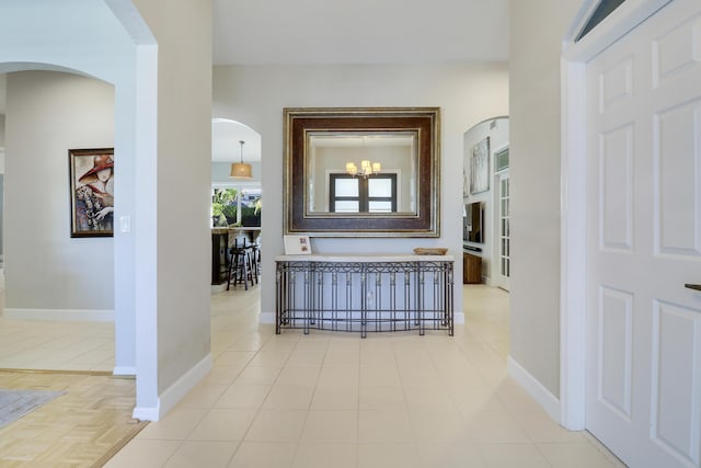 hallway with an inviting chandelier and light tile patterned flooring