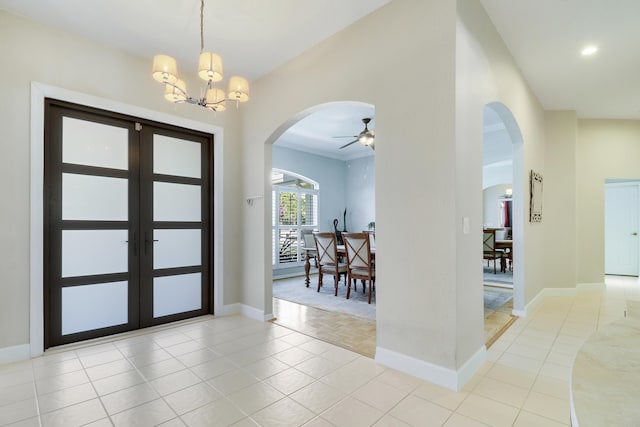 entrance foyer featuring french doors, light tile patterned flooring, and ceiling fan with notable chandelier