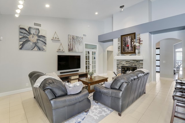 living room with light tile patterned flooring, a stone fireplace, and vaulted ceiling