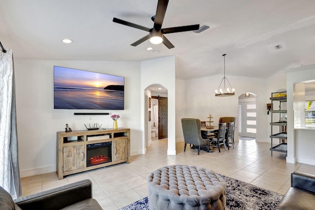 tiled living room with ceiling fan with notable chandelier, a barn door, and vaulted ceiling