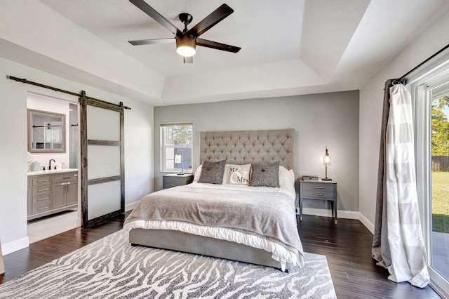 bedroom featuring a raised ceiling, connected bathroom, ceiling fan, and multiple windows