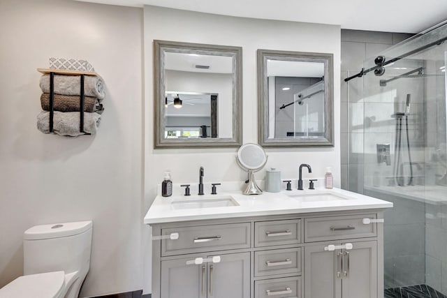 bathroom featuring vanity, ceiling fan, toilet, and a shower with door