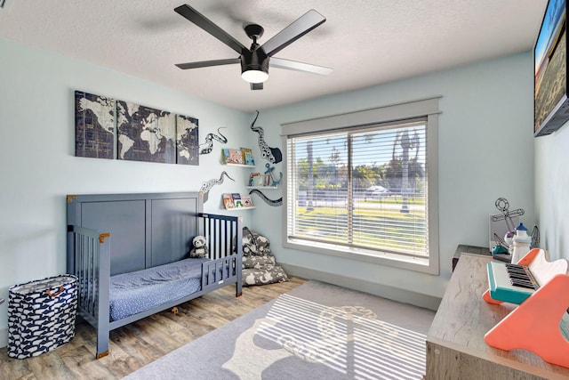 bedroom with hardwood / wood-style floors, ceiling fan, and a textured ceiling