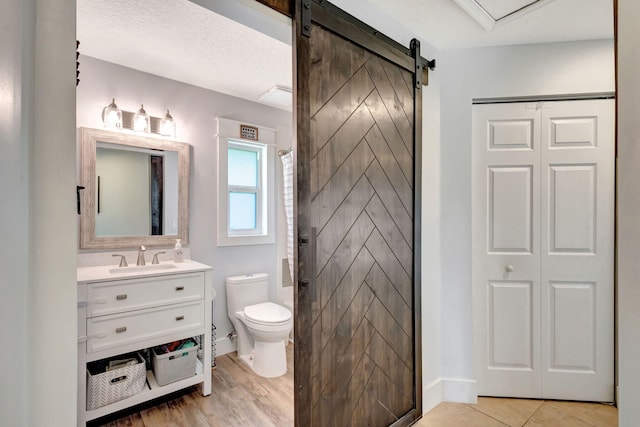 bathroom featuring a shower with curtain, vanity, toilet, and a textured ceiling