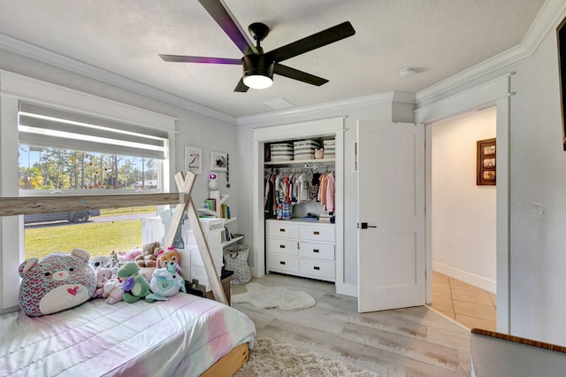 bedroom featuring ornamental molding, a textured ceiling, ceiling fan, light hardwood / wood-style flooring, and a closet