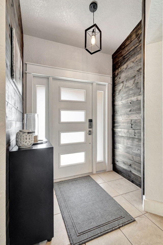 doorway to outside featuring light tile patterned floors, a textured ceiling, and a wealth of natural light