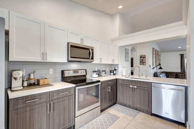 kitchen featuring white cabinetry, sink, stainless steel appliances, tasteful backsplash, and light tile patterned floors