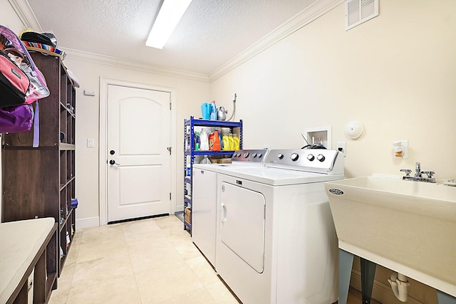 laundry room with a textured ceiling, crown molding, sink, separate washer and dryer, and light tile patterned flooring