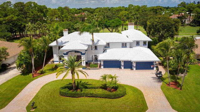 mediterranean / spanish house featuring a garage and a front lawn