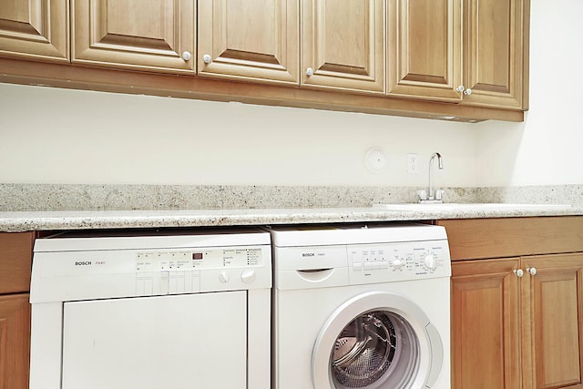 laundry area featuring cabinets, washing machine and dryer, and sink