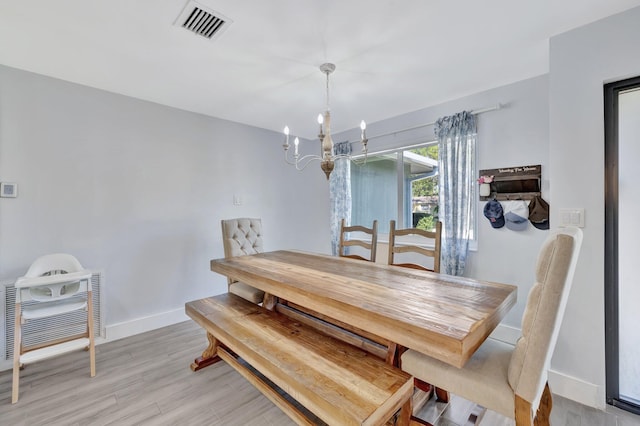 dining room with light hardwood / wood-style flooring and an inviting chandelier