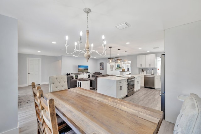 dining area with light hardwood / wood-style floors and a notable chandelier