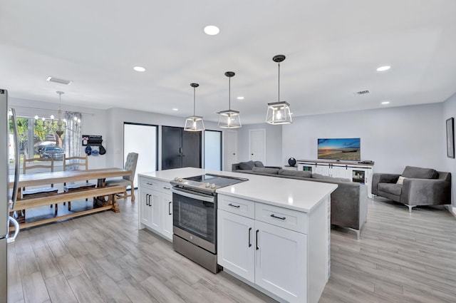 kitchen featuring white cabinetry, stainless steel range with electric cooktop, pendant lighting, and a kitchen island