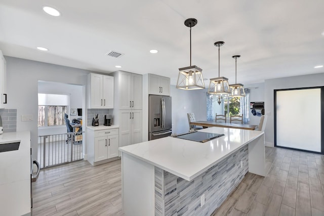 kitchen featuring white cabinetry, hanging light fixtures, stainless steel refrigerator with ice dispenser, black electric cooktop, and decorative backsplash