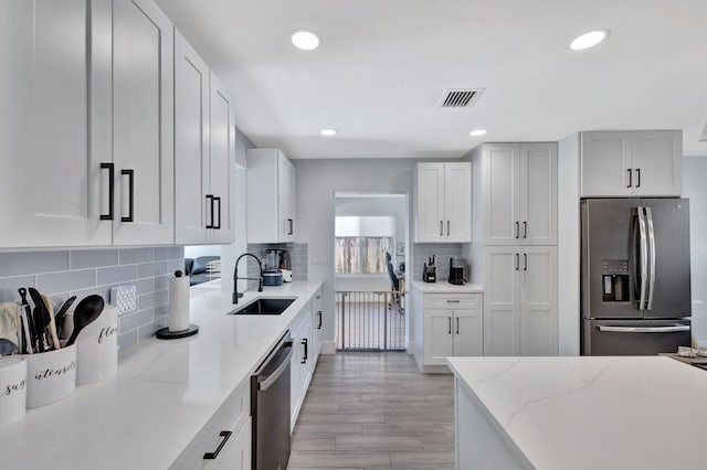 kitchen with decorative backsplash, light stone countertops, sink, and appliances with stainless steel finishes