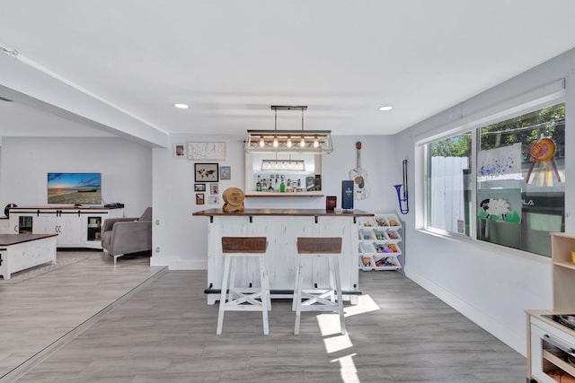 interior space featuring a breakfast bar, hanging light fixtures, and light hardwood / wood-style floors