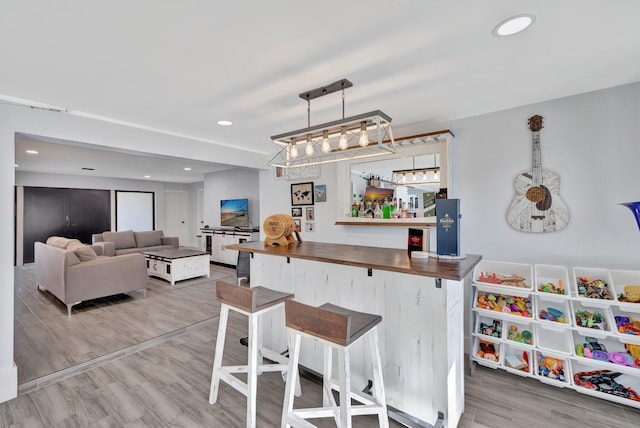 interior space with decorative light fixtures, a kitchen bar, butcher block counters, and wood-type flooring