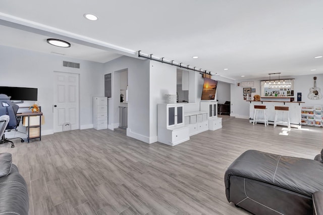 living room featuring indoor bar, light hardwood / wood-style flooring, and a barn door