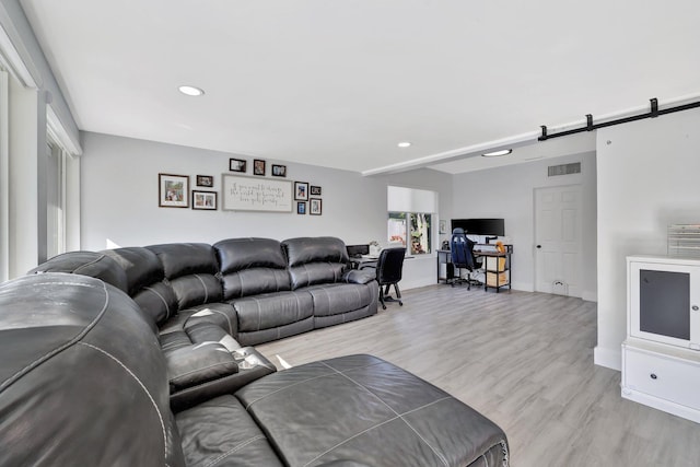 living room with a barn door and light hardwood / wood-style floors