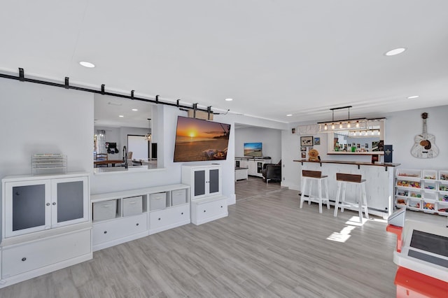 living room with light wood-type flooring, bar area, and a barn door