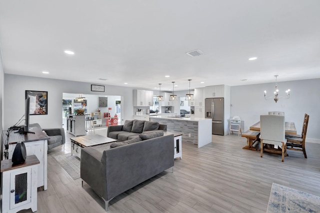 living room featuring a chandelier and light hardwood / wood-style flooring