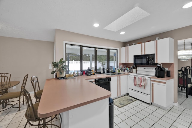 kitchen with kitchen peninsula, a skylight, black appliances, light tile patterned floors, and white cabinets