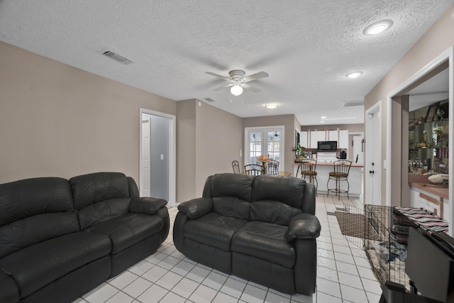 tiled living room with ceiling fan and a textured ceiling