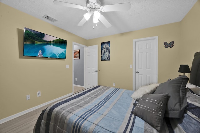 bedroom with ceiling fan, light wood-type flooring, and a textured ceiling