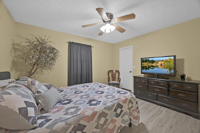 bedroom featuring ceiling fan, a textured ceiling, and light hardwood / wood-style flooring