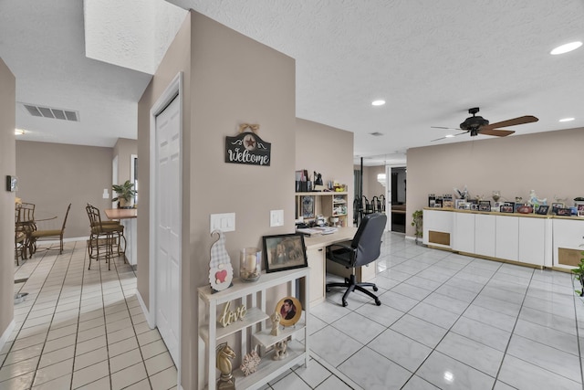 office space with a textured ceiling, ceiling fan, and light tile patterned flooring